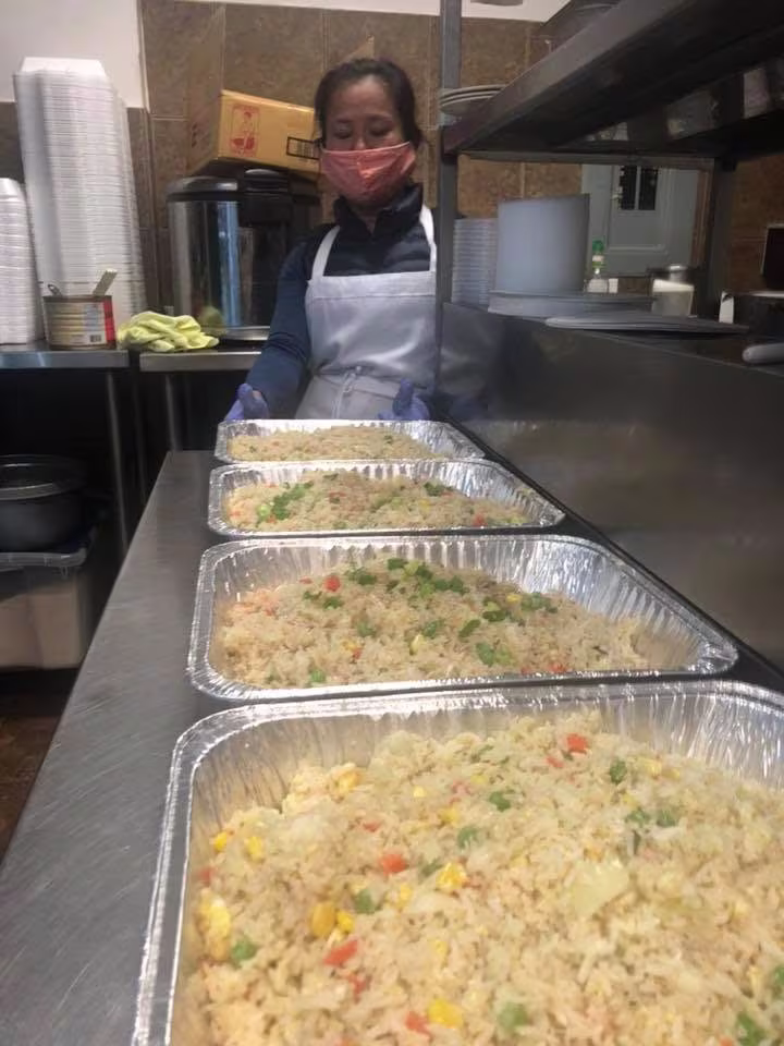 Cook packing fried rice trays in a My-Thai kitchen